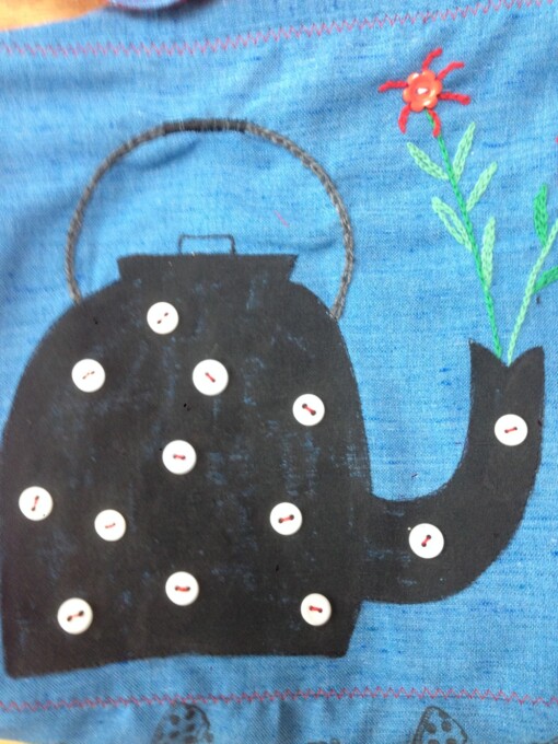 Blauwe tas met theepot en geborduurde bloemen