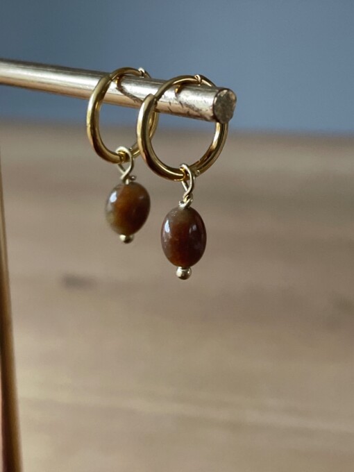 Gouden oorbellen met bruine edelsteen.