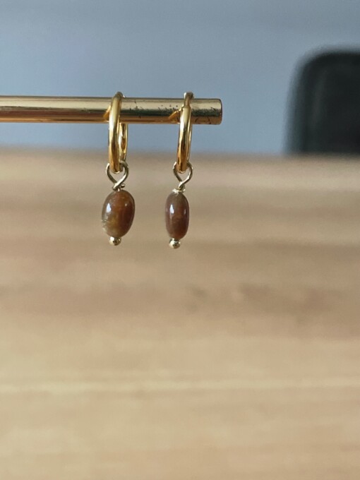Gouden oorbellen met bruine edelsteen.