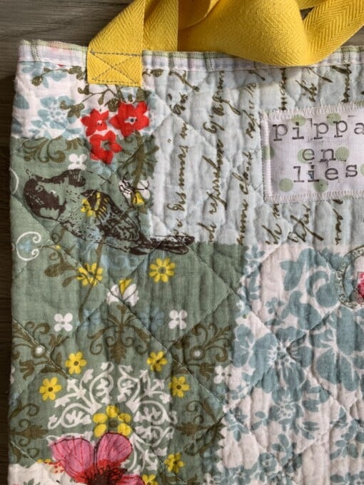 Tote bag van een doorgestikte sprei met bloemen, vlinders en vogels