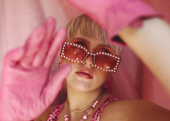 Vrouw met roze accessoires: zonnebril, sieraden en handschoenen