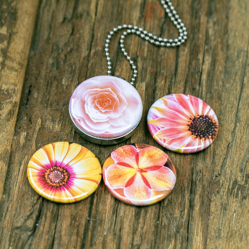 Foto medaillon ketting met 4 verschillende verwisselbare voorkanten met close up foto`s van zacht roze,gele en zalm kleurige bloemen, binnen in komt de foto die je graag dicht bij je draagt