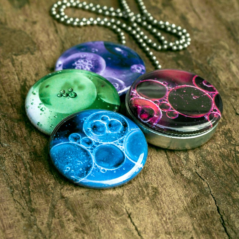 Foto medaillon ketting met 4 verschillende verwisselbare voorkanten met close up foto`s van olie bellen in verschillende kleuren.