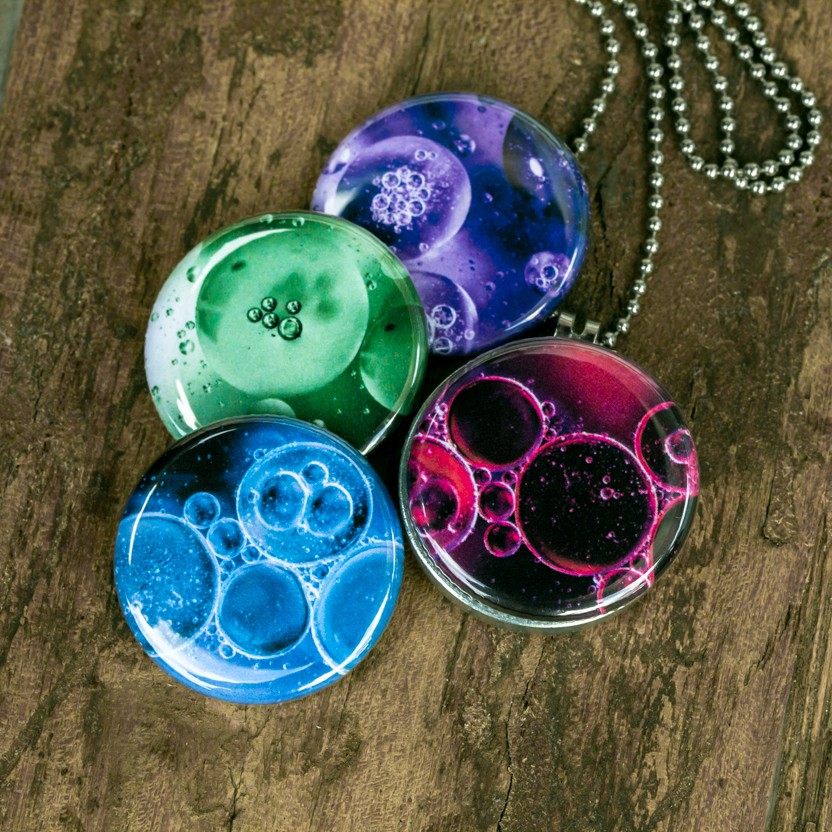 Foto medaillon ketting met 4 verschillende verwisselbare voorkanten met close up foto`s van olie bellen in verschillende kleuren.