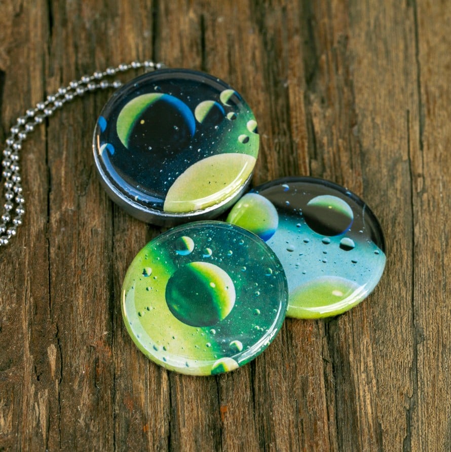 Roestvrij stalen fotomedaillon ketting met drie verschillende verwisselbare voorkanten met close up foto`s van olie druppels in water, het lijken bijna planeten. Rvs/roesvrij stalen fotomedaillon. Voor het dicht bij je dragen van je favoriete foto.