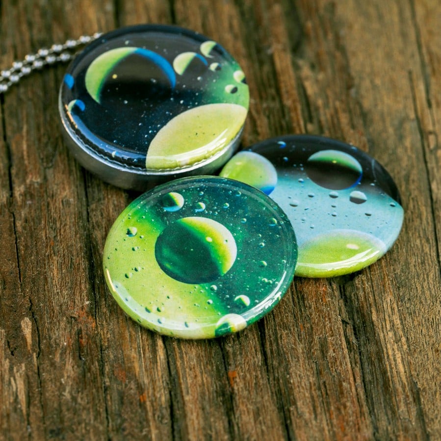 Roestvrij stalen fotomedaillon ketting met drie verschillende verwisselbare voorkanten met close up foto`s van olie druppels in water, het lijken bijna planeten. Rvs/roesvrij stalen fotomedaillon. Voor het dicht bij je dragen van je favoriete foto.