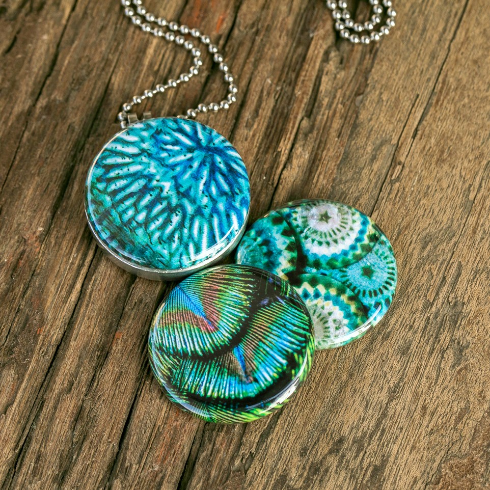 Roestvrij stalen fotomedaillon ketting in teal blauw met drie verschillende verwisselbare voorkanten met close up foto`s in pauw blauw.Pauwenveer close up. Rvs/roesvrij stalen fotomedaillon. Voor het dicht bij je dragen van je speciale  foto.