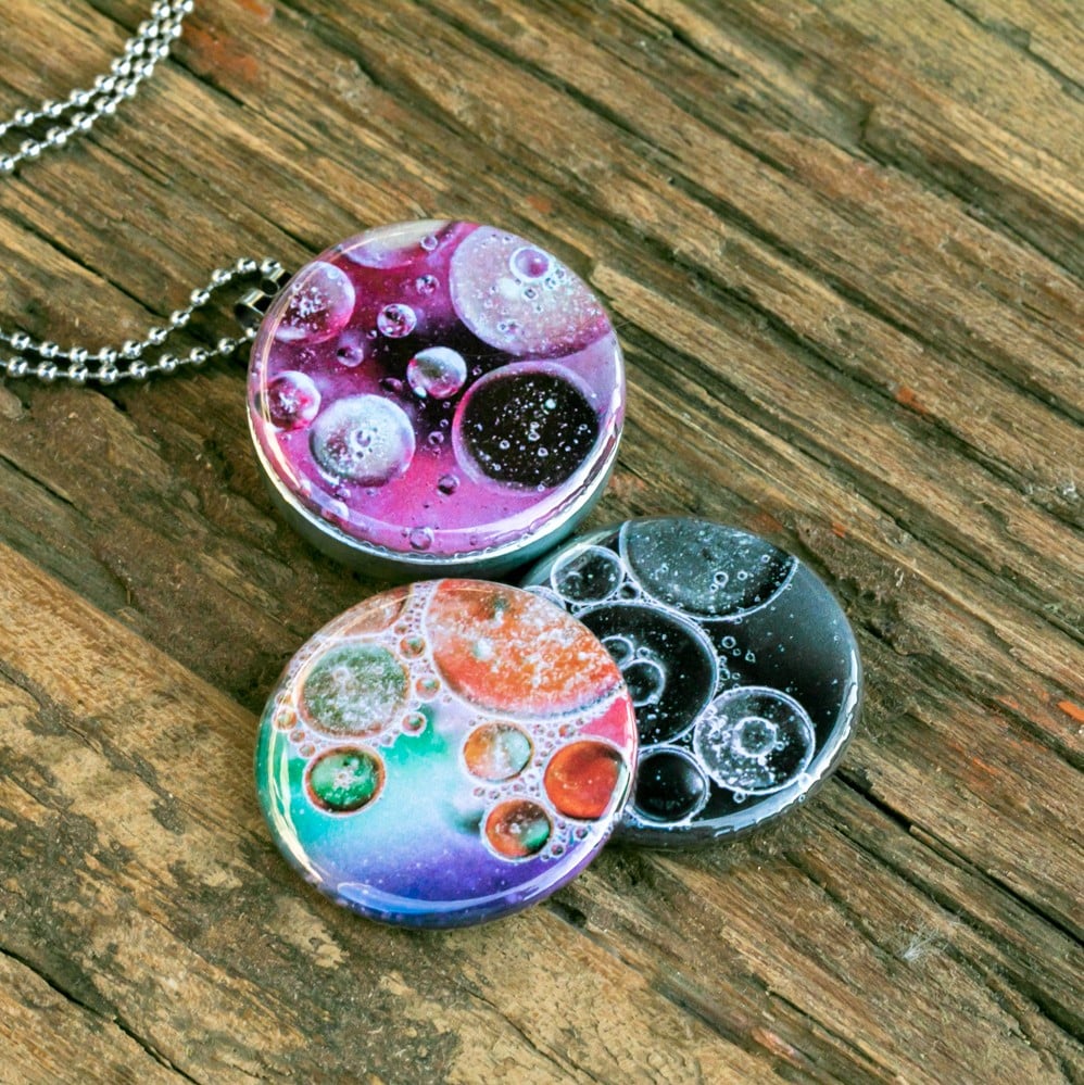 Roestvrij stalen fotomedaillon ketting met drie verschillende verwisselbare voorkanten met close up foto`s van olie druppels in water, in mooie tinten en zwart wit.Rvs/roesvrij stalen fotomedaillon. Voor het dicht bij je dragen van je favoriete foto.